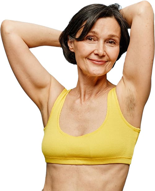 Ältere Frau im gelben Sport-BH zeigt ihre haarfreien Achseln.